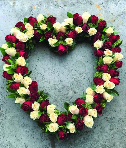 A heart shaped outline full of red and white roses with some greenery.