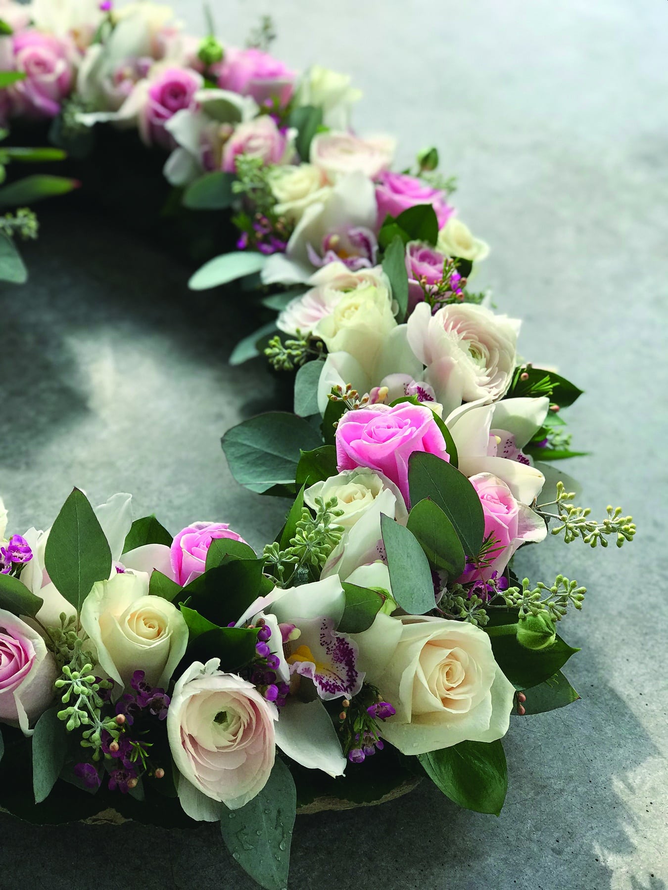 Close up of the roses, rununculus, and cymbidium orchids used in this open heart bereavement design.