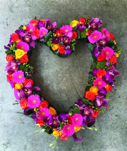 A bright pink, purple and orange open heart design. Made with orange roses, pink cymbidium orchids, hot pink gerberas, yellow freesias, dianthus, yellow rununculus, puple dendrobium orchids, and dark pink calla lilies.