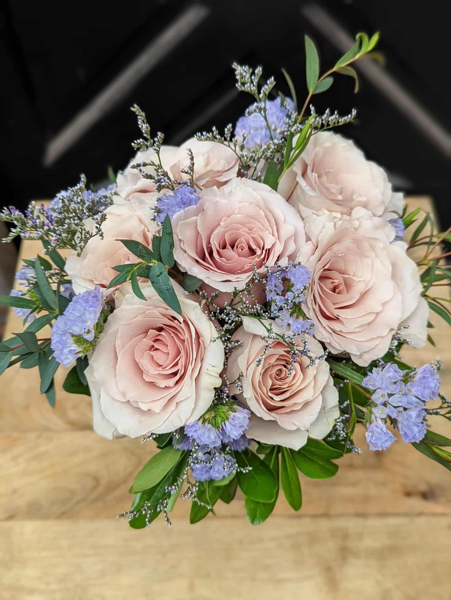 A small bouquet of blush roses with blue statice, limonium and minimal greenery.