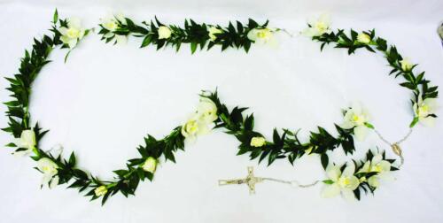 Ruscus, white cymbidium orchid blooms, and white roses formed into a necklace shape with a gold corss.