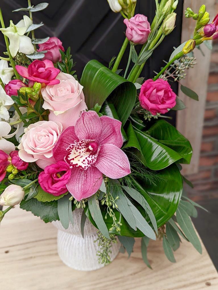 Close up of the pink cymbidium orchids, roses and lisianthus in a Europen style floral arrangement,