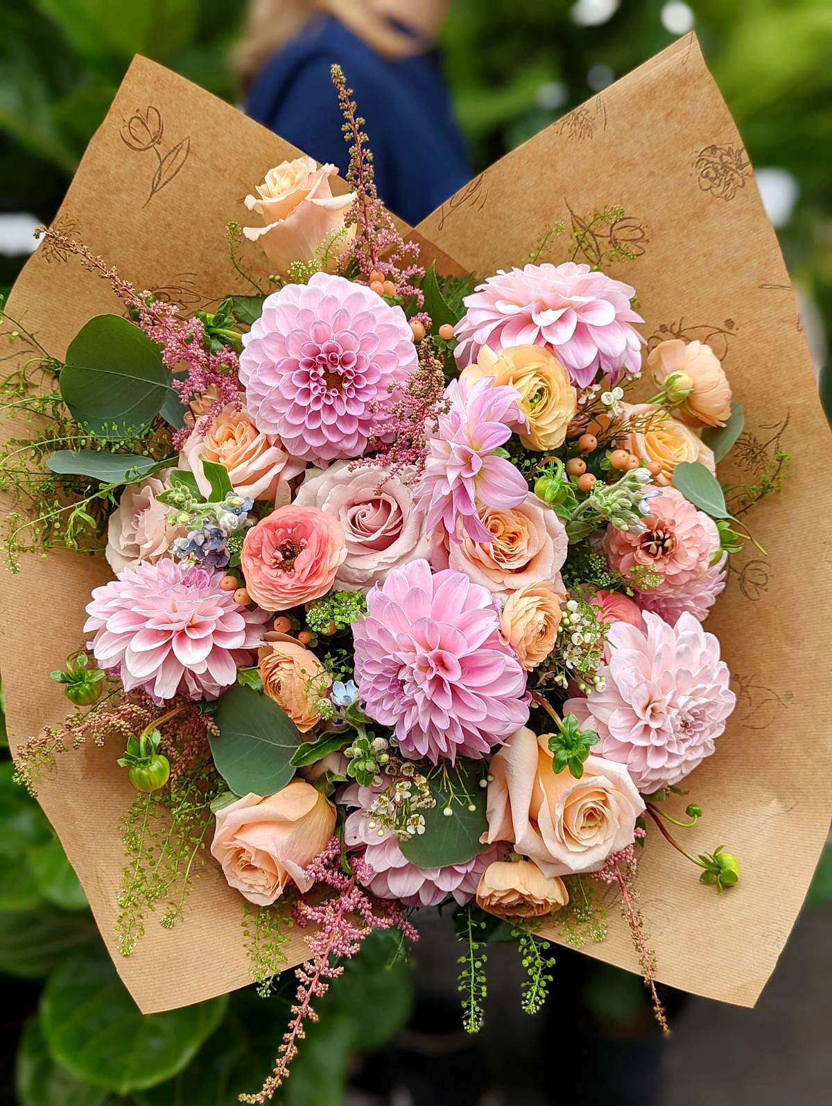 A generous blush and peach handtied bouquet with lots of dahlias, roses, and ranunculus.