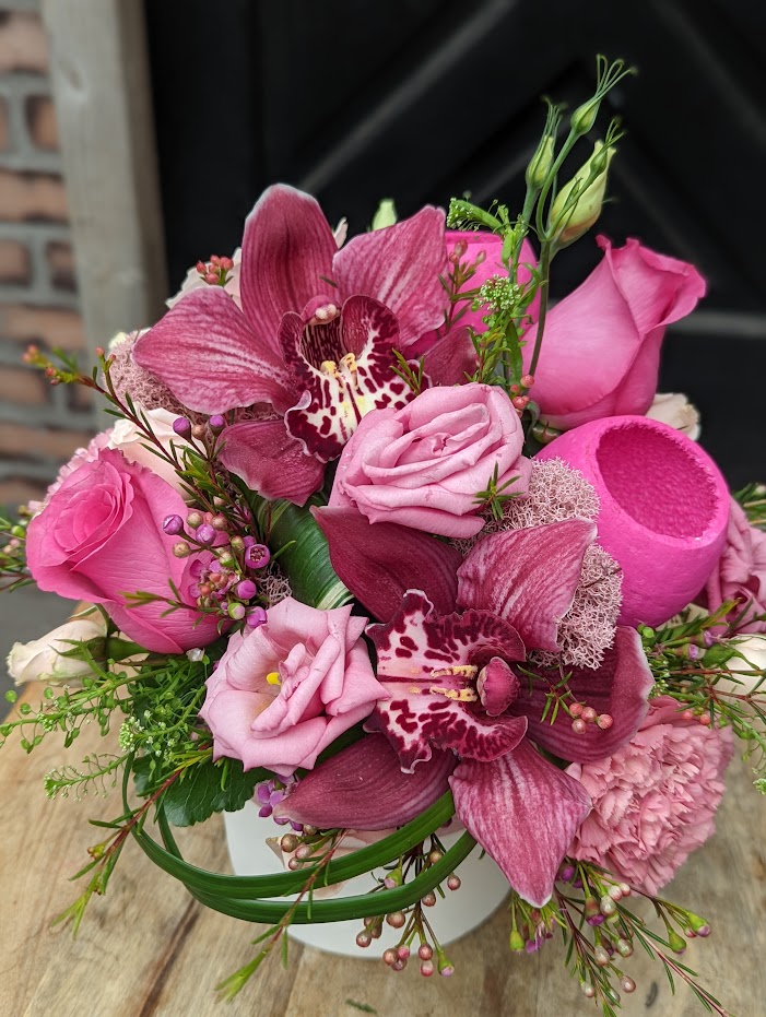 A hot pink European style arrangement in a white ceramic container.