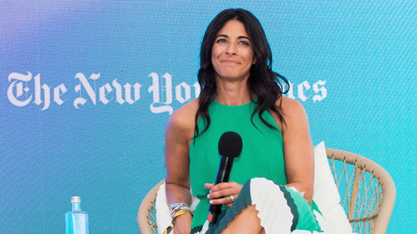 Joy Robins, global chief advertising officer, The New York Times, speaks at the 2023 Cannes Lions Festival of Creativity. Robins, wearing a green dress, sits in a rattan chair in front of an LED screen with “The New York Times” logo.
