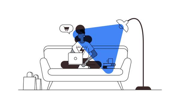 Una mujer, sentada en un sillón, mira una computadora. A un costado, unas bolsas de compras y un globo de diálogo con un carrito de shopping. A otro costado, una lámpara alta. Sobre la escena, un triángulo azul sobreimpreso.