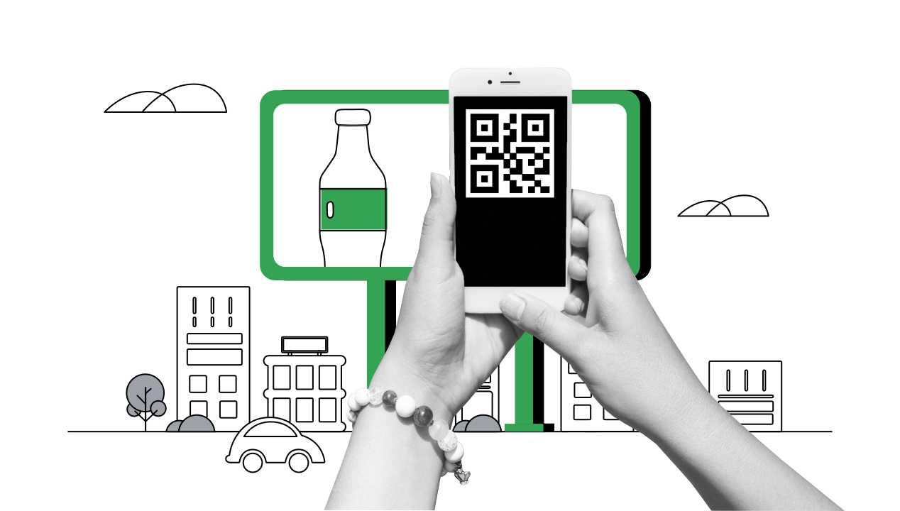 Unas manos en blanco y negro con un telefóno en la mano escanean un QR de un aviso de vía pública. Detrás un cartel en verde con una botella con etiqueta verde y el perfil de una ciudad.