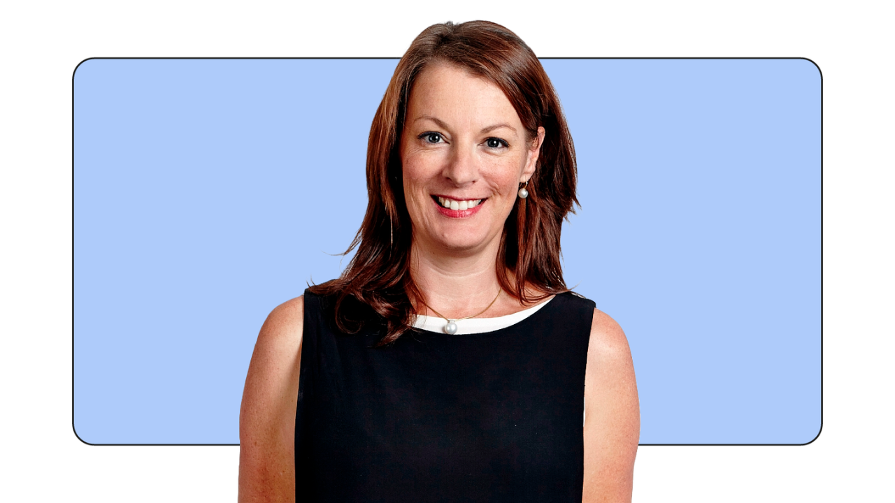 Karen Stocks, VP of Global Measurement Solutions di Google, sorride in piedi davanti a un rettangolo azzurro. Ha la pelle chiara e capelli castani lunghi fino alle spalle. Indossa un abito nero senza maniche con dettagli bianchi sulla scollatura.