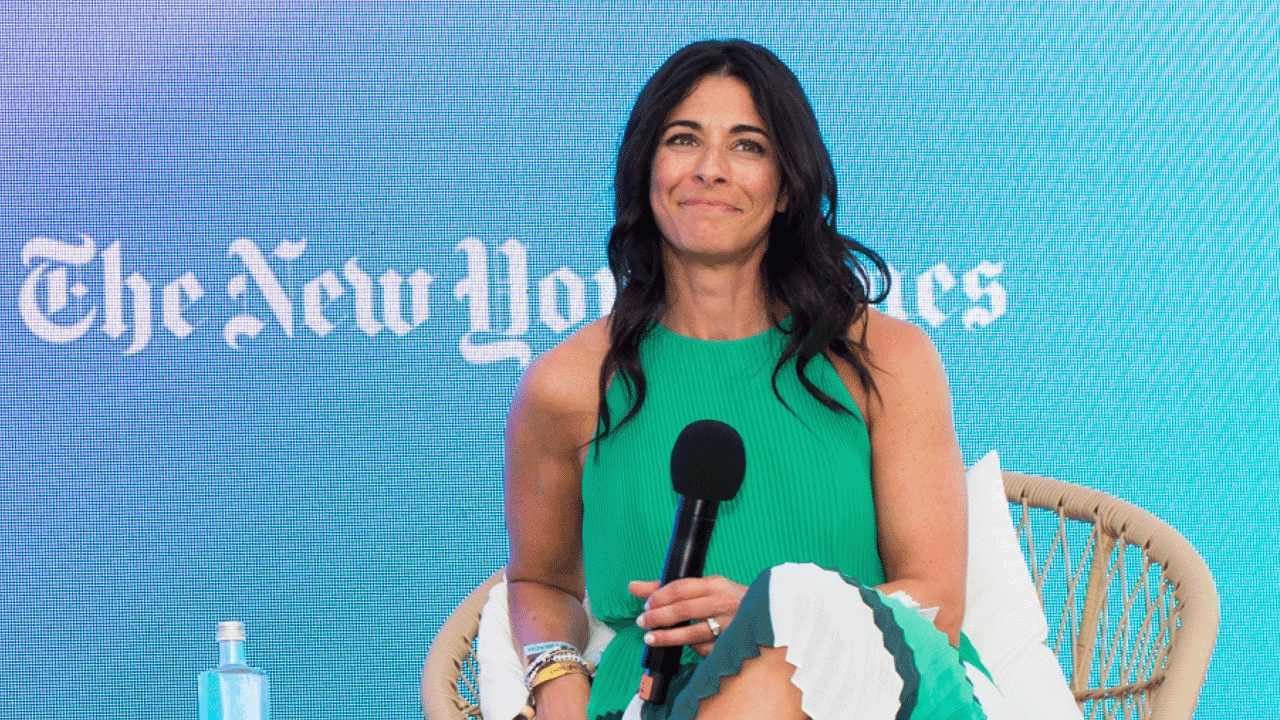 Joy Robins, global chief advertising officer pour le New York Times, s'exprime lors du Festival international de la créativité 2023 de Cannes. Joy Robins, vêtue d'une robe verte, est assise sur une chaise en rotin devant un écran LED sur lequel figure le