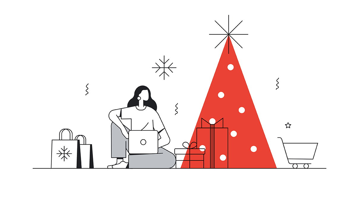 A long-haired woman works on her laptop next to a red Christmas tree as snow falls. Shopping bags, gifts, and a trolley surround her.
