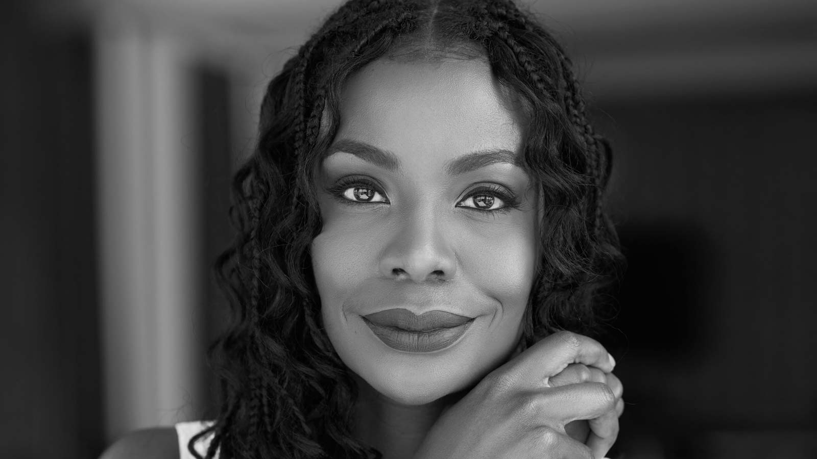 Tanneasha Gordon, principal, data and trust practice lead at Deloitte and Touche LLC, looks into the camera and smiles, with her chin resting on her folded hands. Gordon has dark skin, dark eyes, and dark wavy hair.