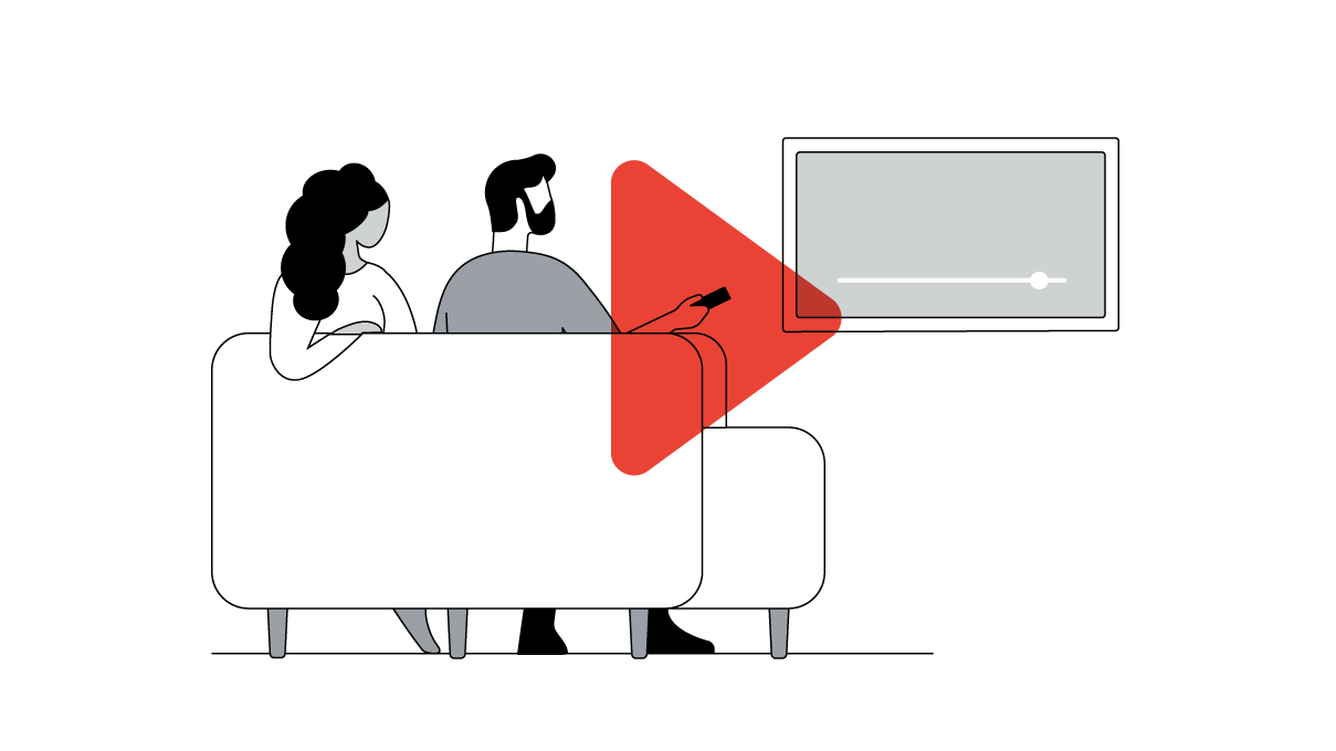 A person with long, dark wavy hair and medium skin sits next to a person with short, dark hair, a beard, and light skin on a living room couch and, together, they watch YouTube from their connected TV.