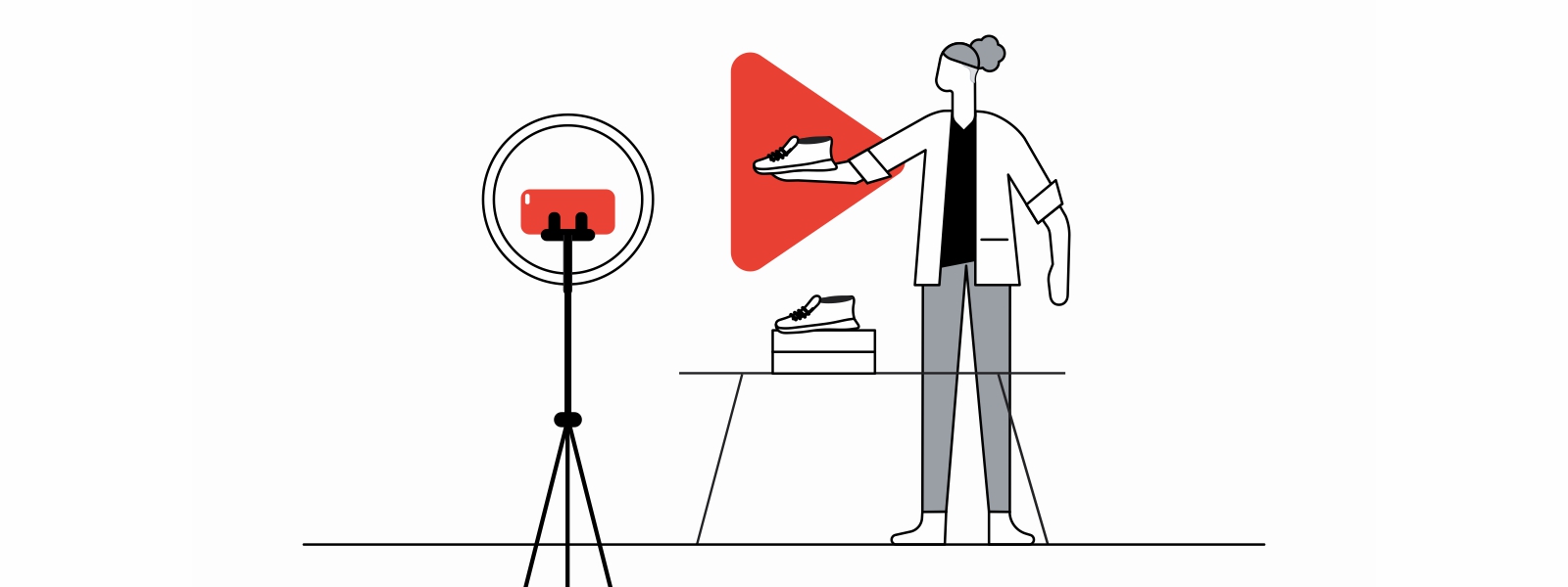 Una mujer con pelo enrulado y saco blanco muestra a la cámara un par de zapatos. Detrás de eso, el logo de YouTube en rojo. A la izquierda, un trípode con un teléfono móvil apuntando al zapato.
