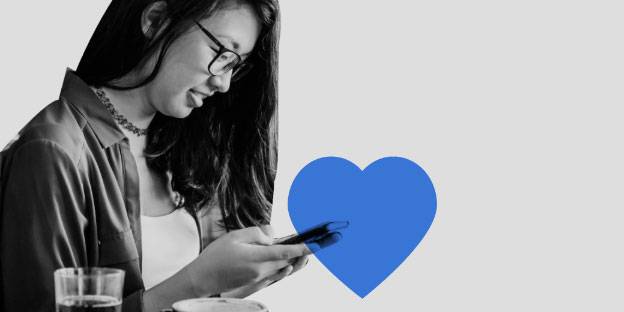 A woman smiles while looking at her phone.