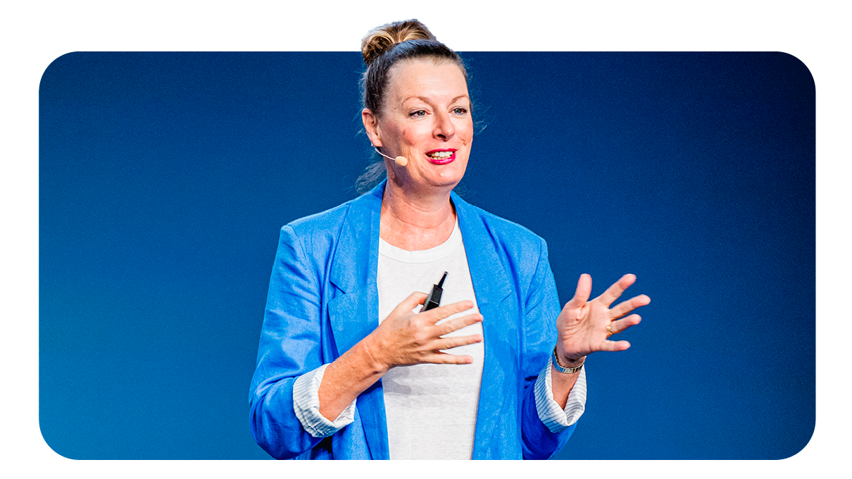 Karen Stocks, vicepresidenta de soluciones de medición globales en Google, dando una conferencia. La mujer, de piel clara y pelo castaño en un moño, lleva una americana larga de lino azul intenso encima de una camiseta blanca con pantalones oscuros.