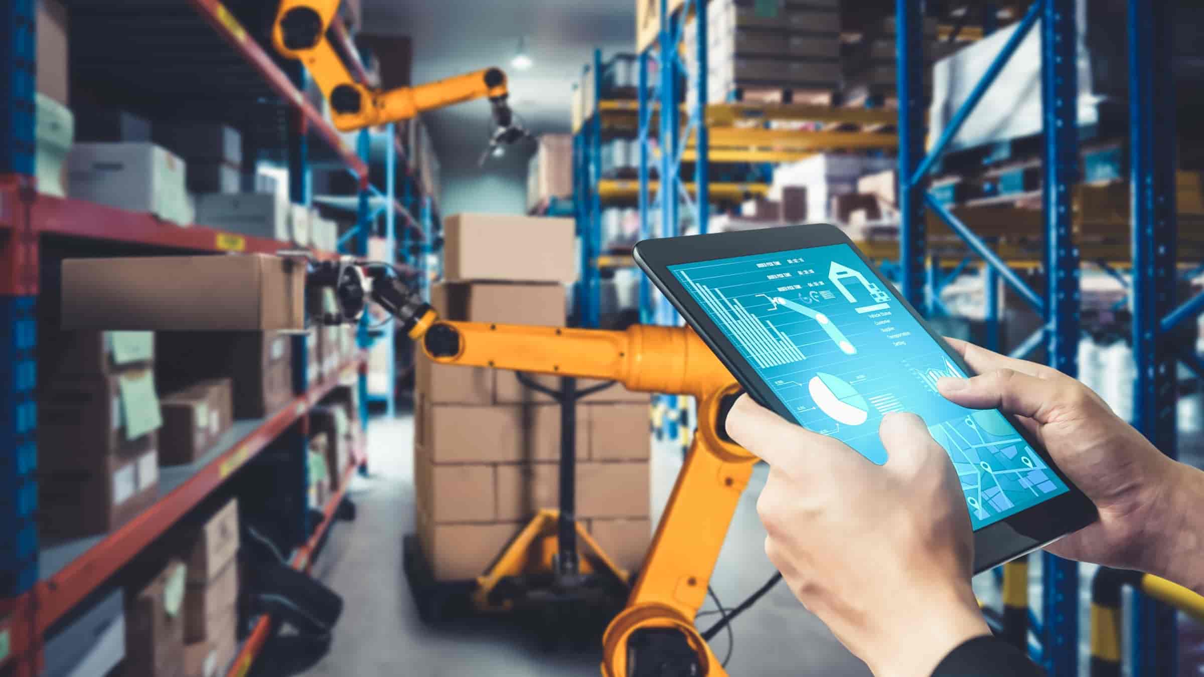 automatyzacja-magazynu-wms-agv-automatyzacja-raportowania Pracownik magazynu z tabletem obok robota AGV symbolizujący automatyzację magazynu i logistyki