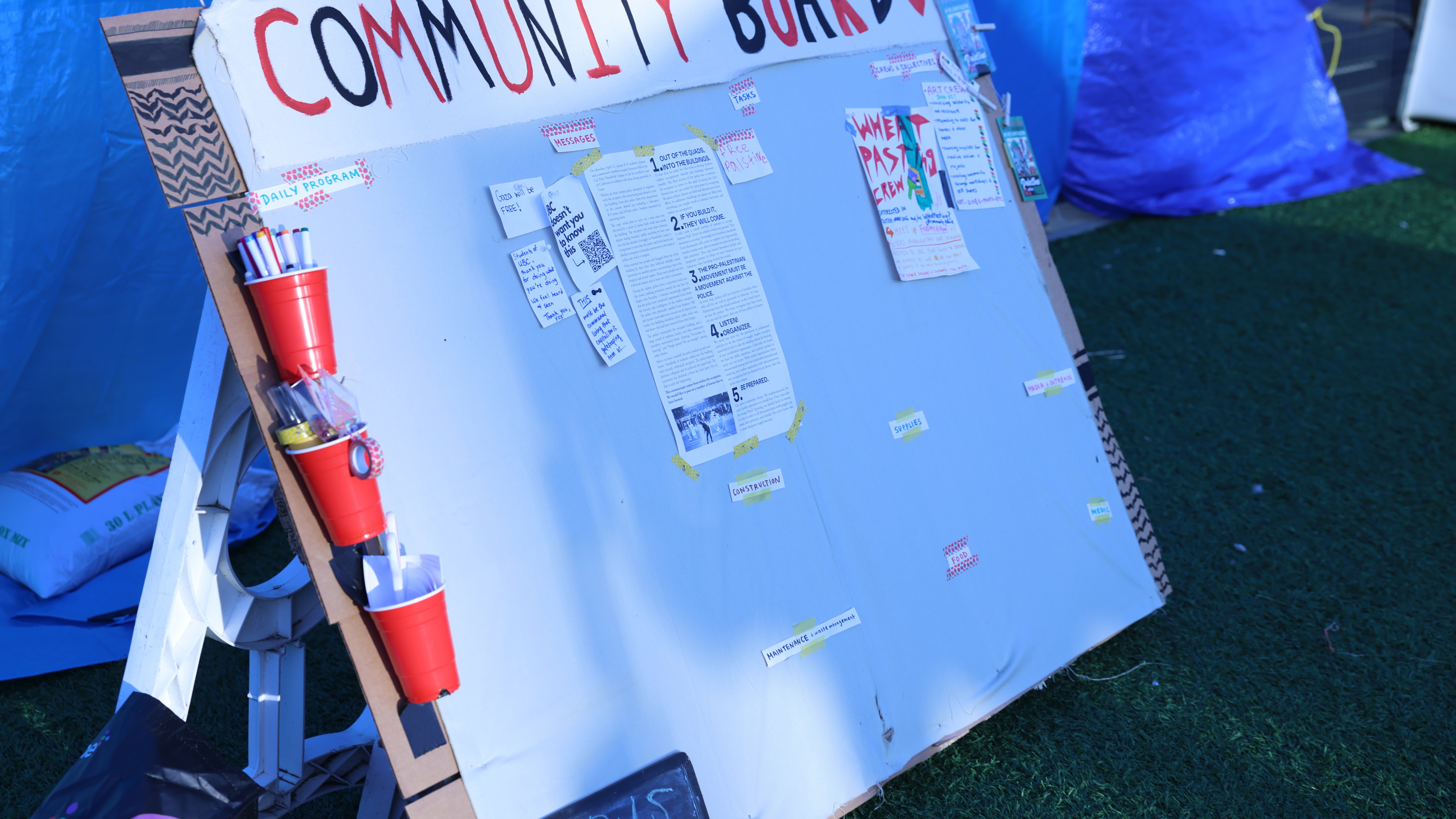 A community board in the encampment, lit up by the sunrise.