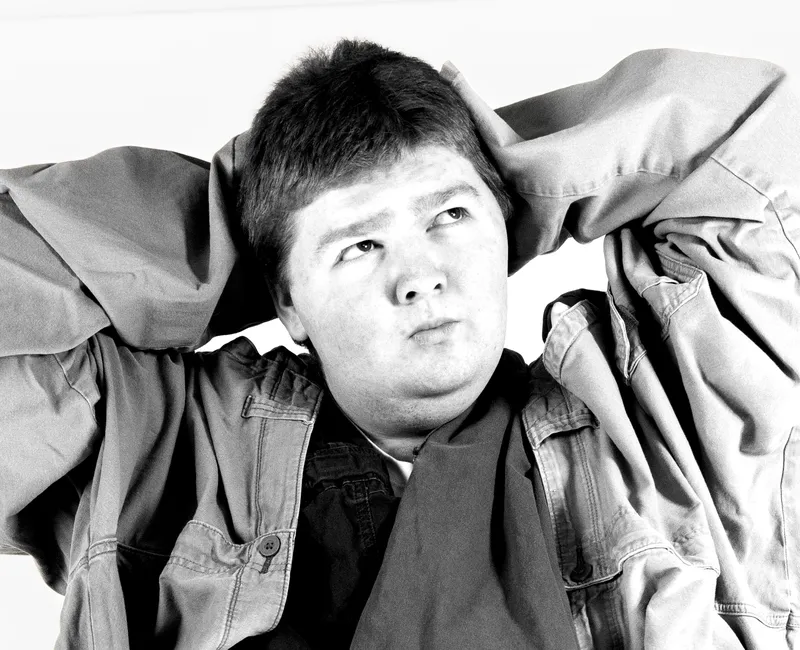 A greyscale image of a student wearing several pairs of pants around their body.