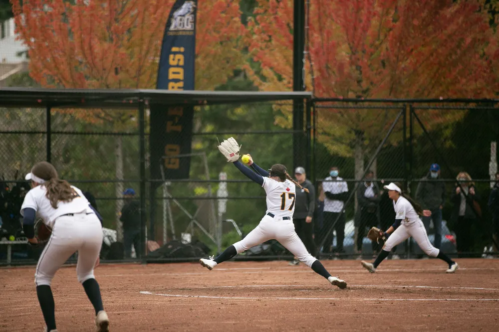 A softball player begins their pitching motion