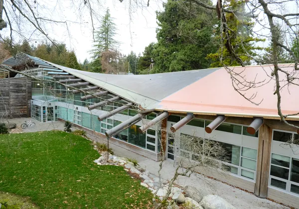 The outside of the First Nations Longhouse at UBC, a building with long beams and a slightly curved roof.