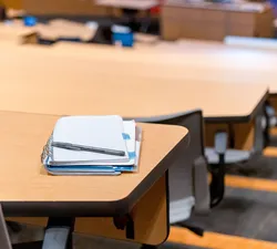 Inside a lecture hall, a pen sits on top of a notebook.