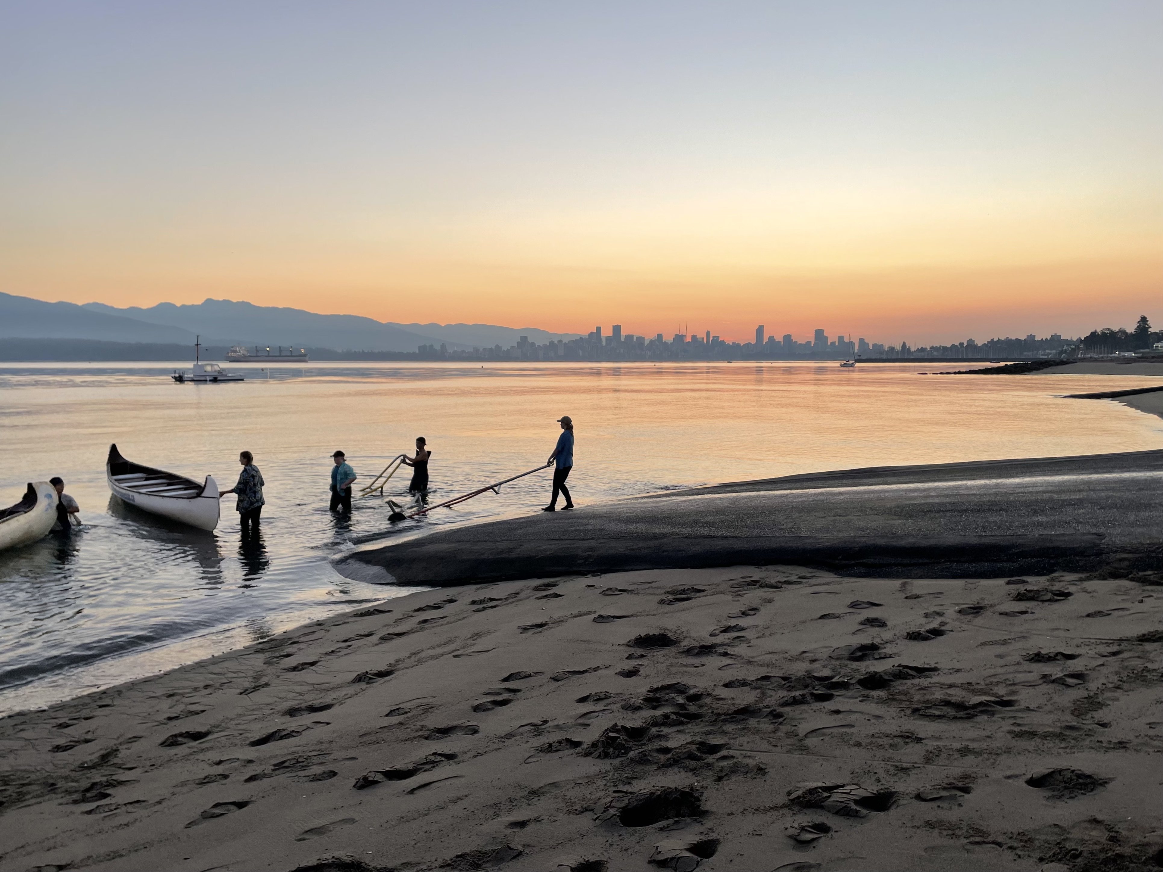 Student volunteers in wet suits and Hawaiian shirts pull voyageur canoes into the icy morning water.