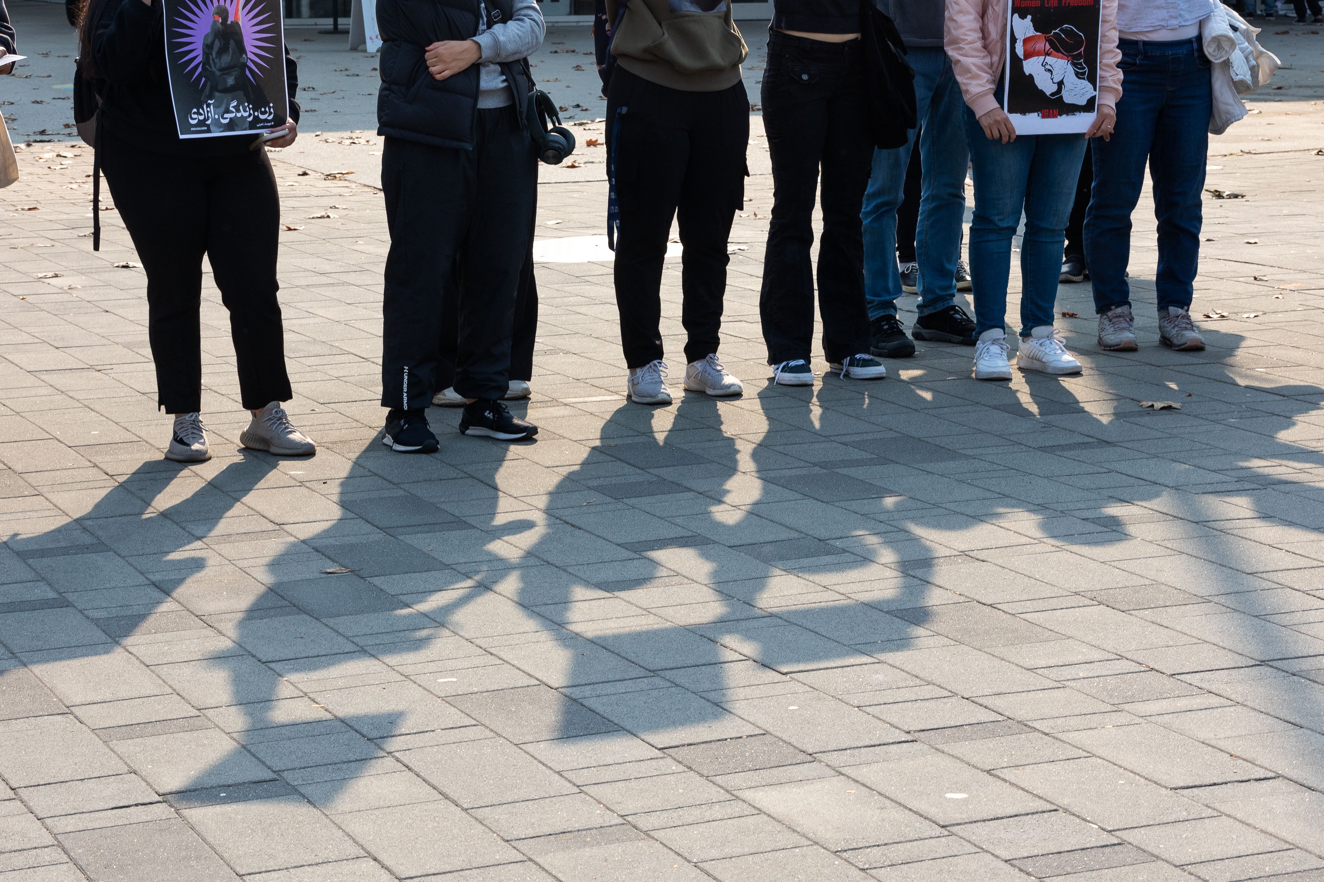 Protestors with signs cast shadows in the plaza outside the bookstore.