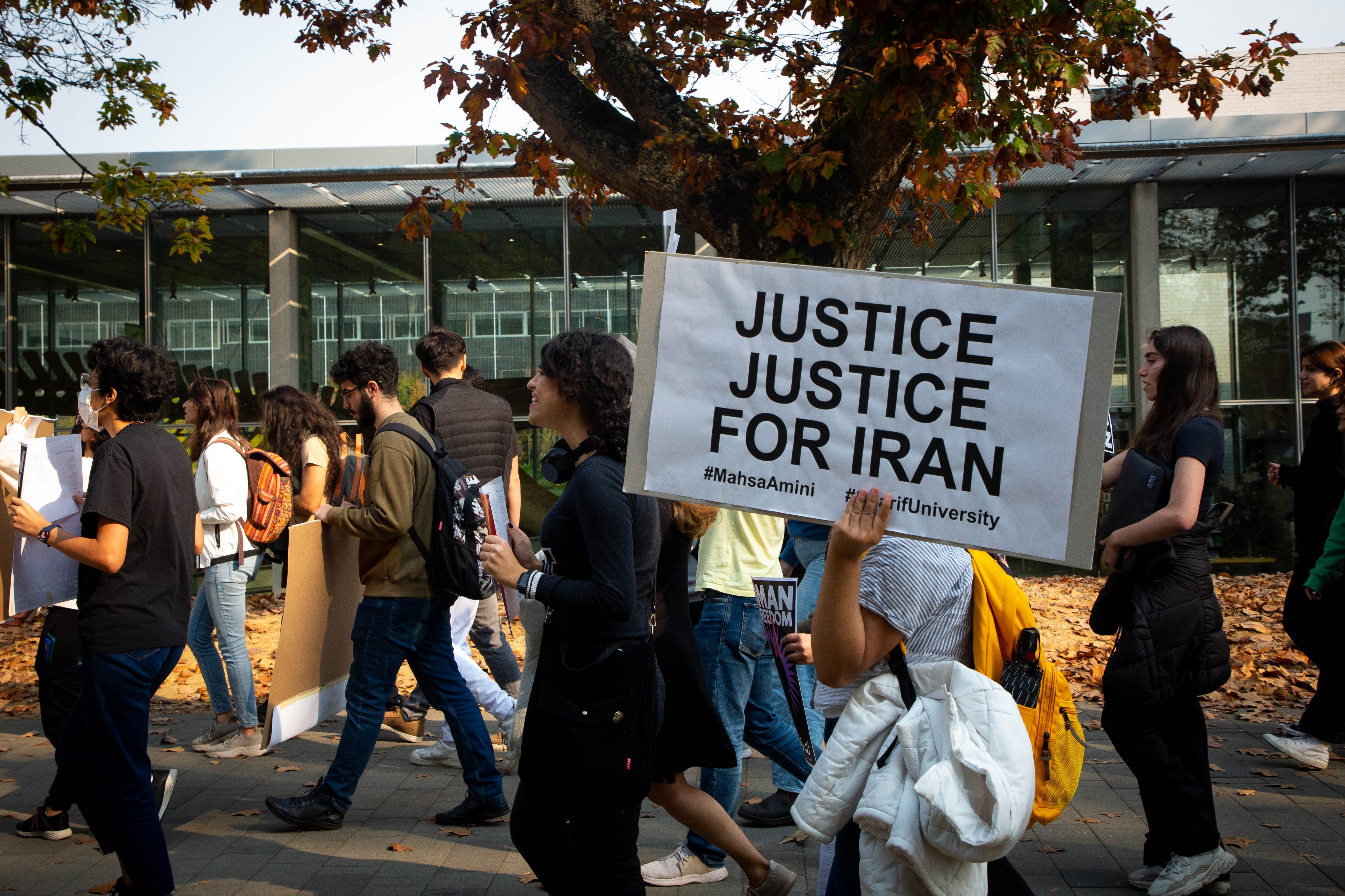 Marchers hold signs calling for justice from both Iranian and Canadian governments as they parade down Main Mall.