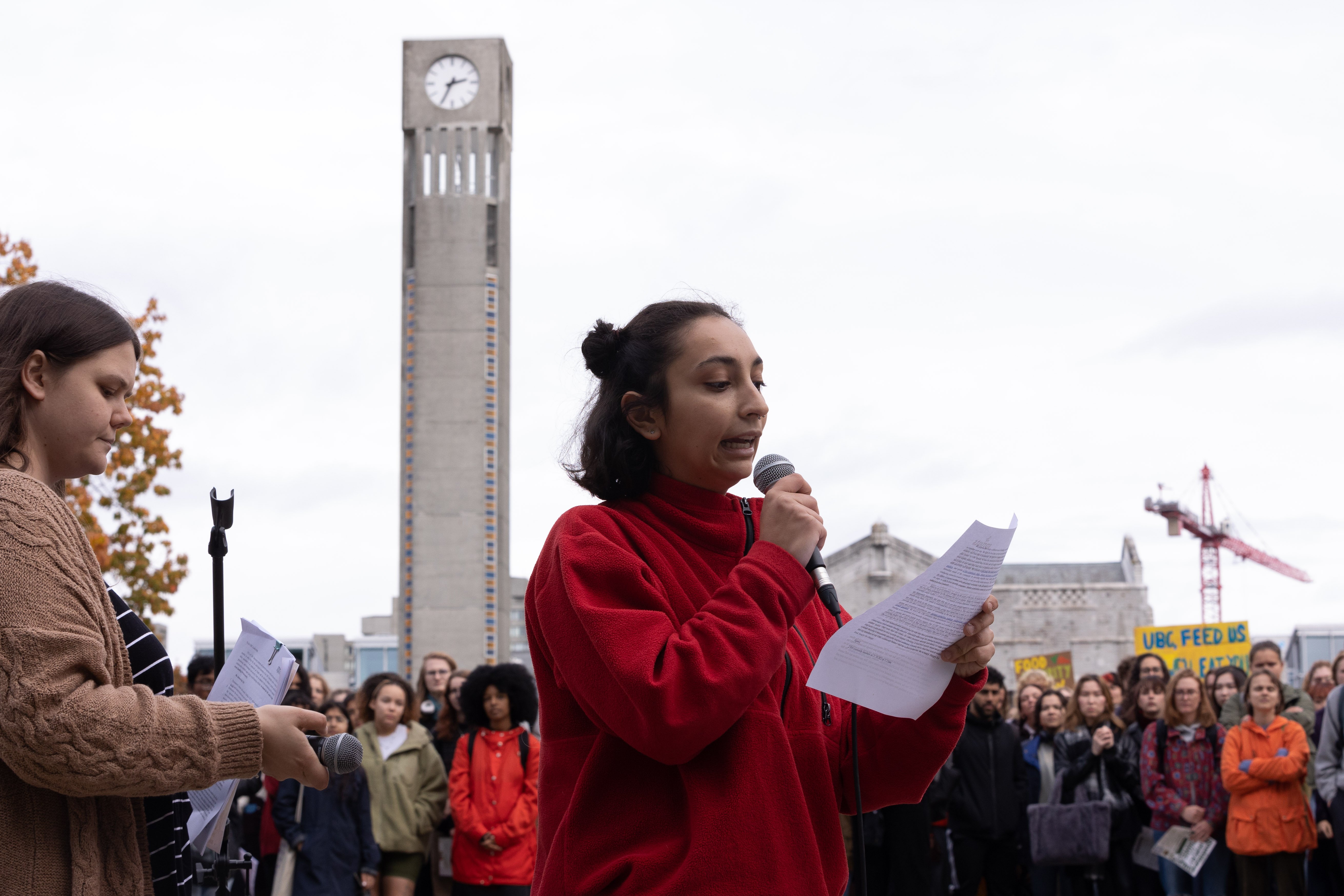 Sprouts co-presidents Delanie Austin and Gizel Gedik address crowds of students before Koerner Library with Irving K. Barber Learning Centre in the background.