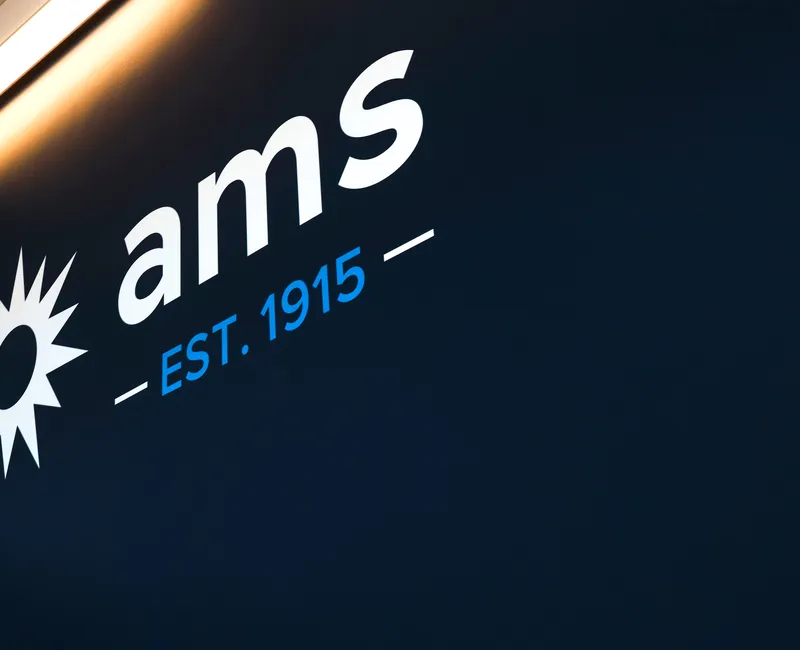 The AMS logo is displayed on a wall.