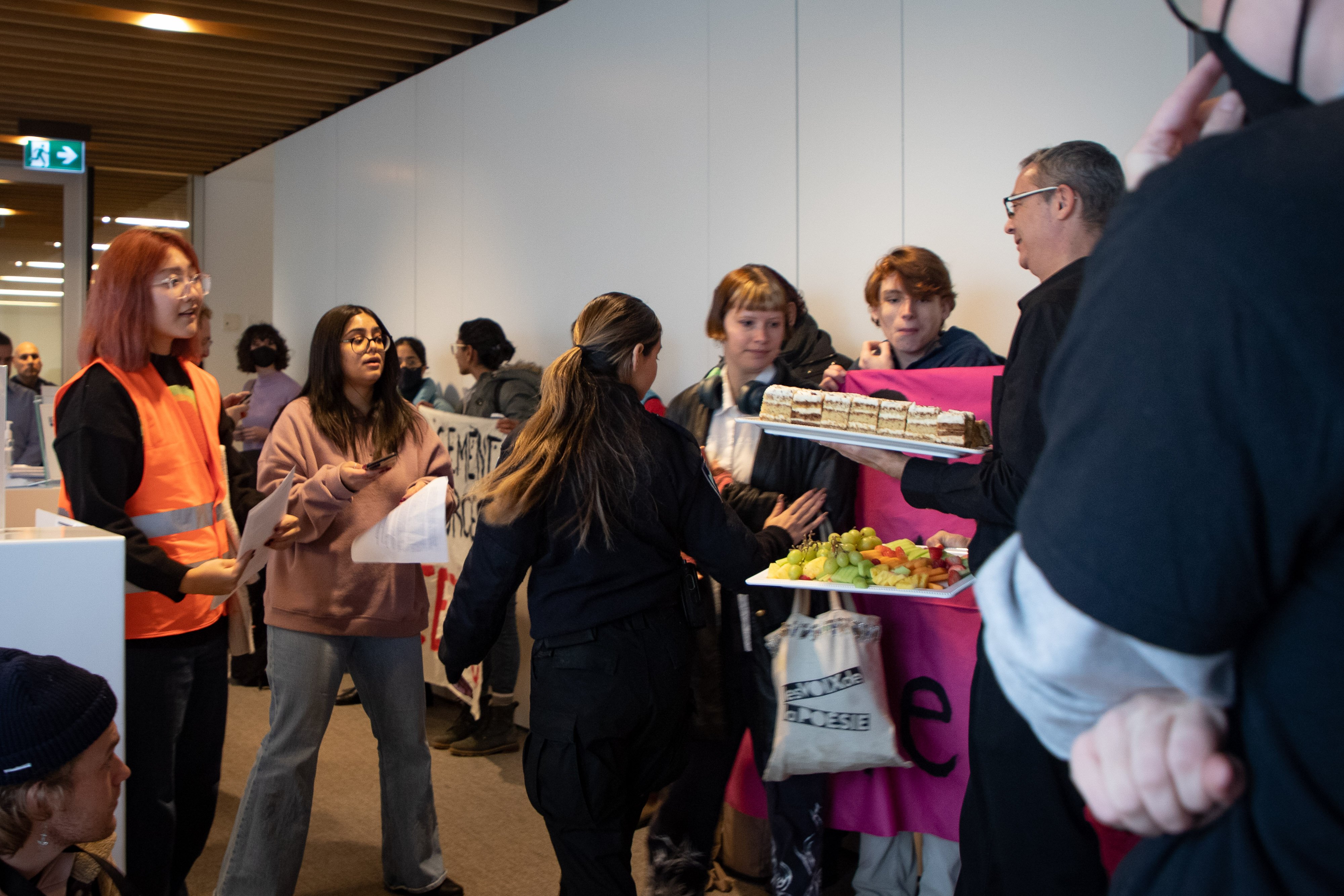 Students shout 'Let them eat cake' as staff carry a large cake into the boardroom.