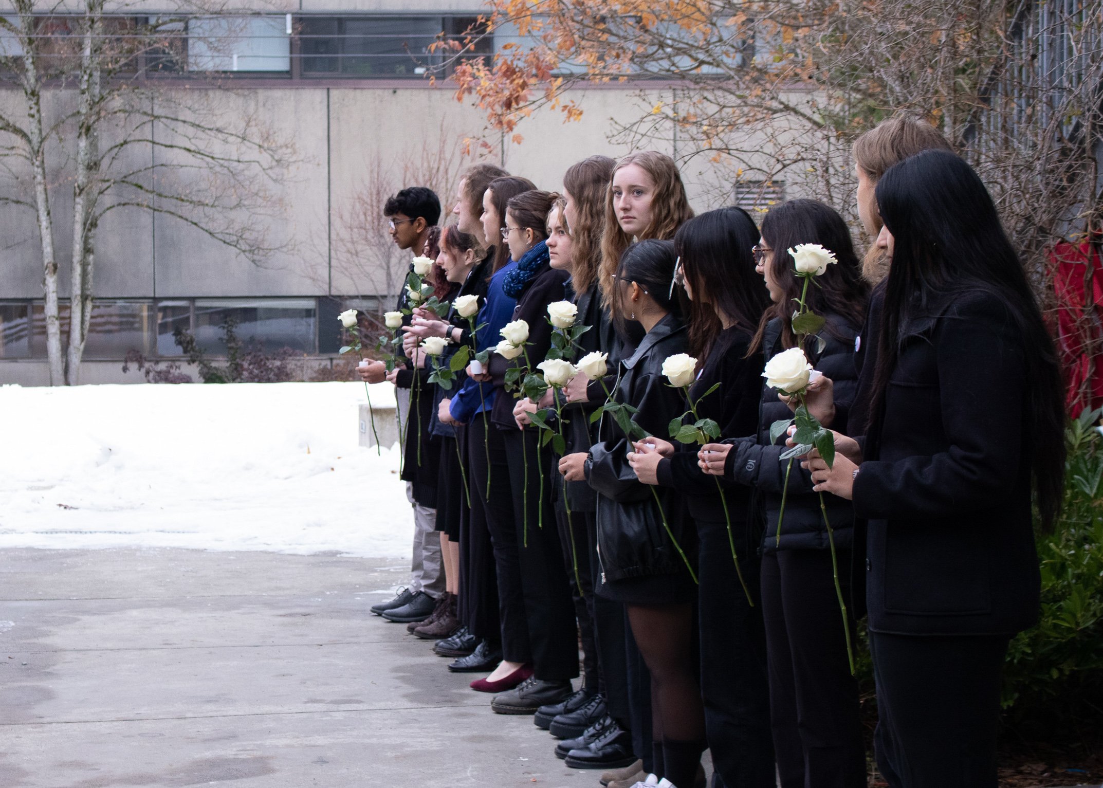 Students in the Engineering Student Centre courtyard bearing flowers and candles.