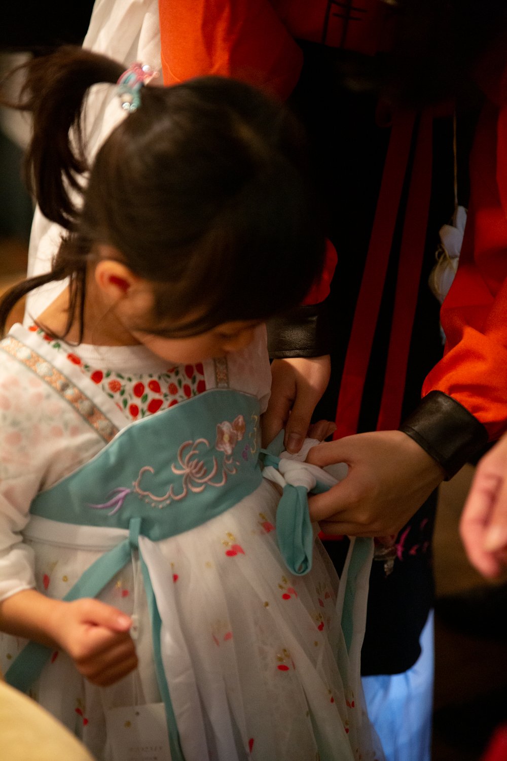 Members of the Vancouver Hanfu Culture Society help dress a young visitor.