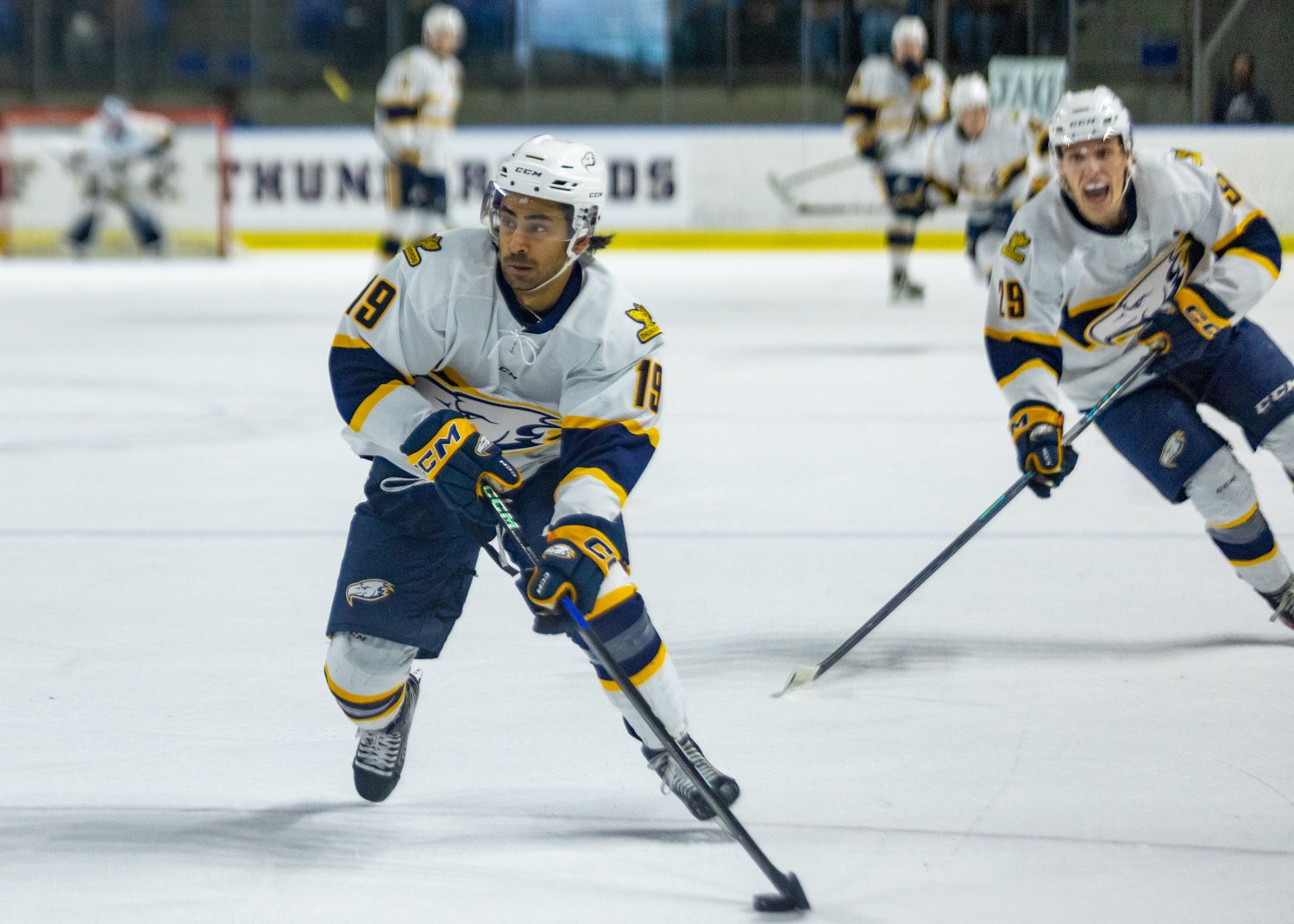 Jordan Sandhu (#19) carries the puck down the ice.