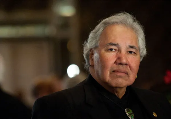 A photo portrait of Murray Sinclair wearing a button-up black dress shirt and looking into the camera with a serious expression.