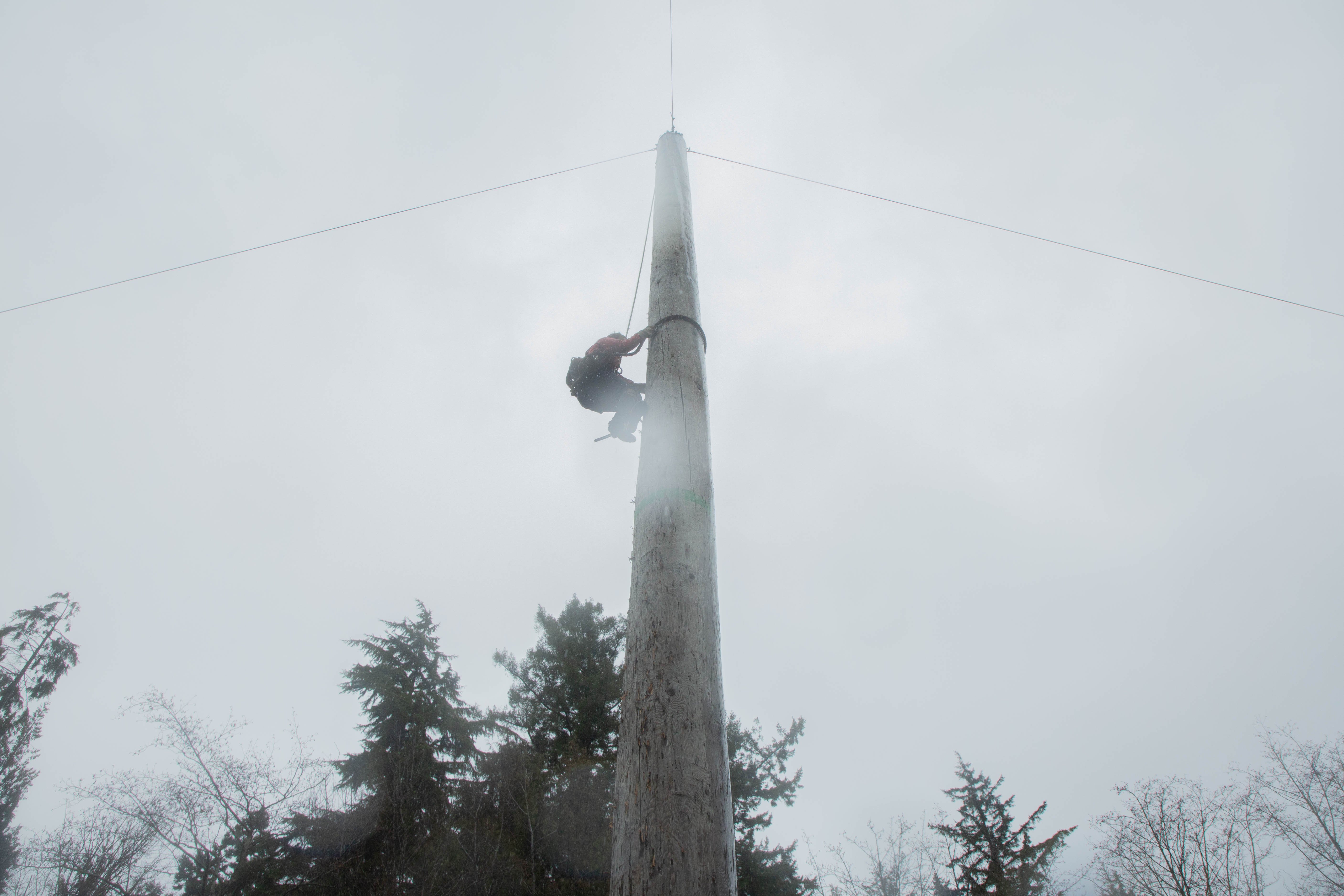 A club member makes their way up a 40 foot pole under the rainy Vancouver skies.