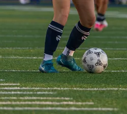 A player dribbles a soccer ball on a turf field.