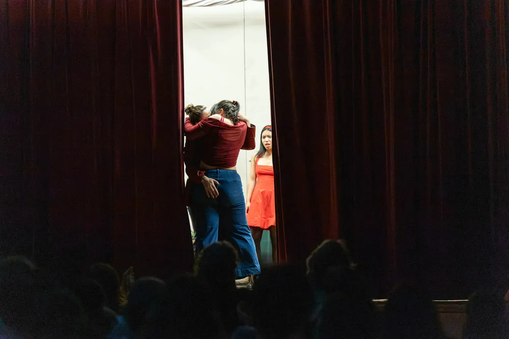 Two people are kissing as a curtain closes on them