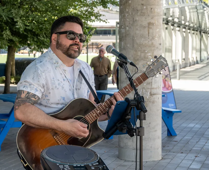 Performer playing guitar at Summer Sounds at UBC.