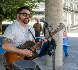 Performer playing guitar at Summer Sounds at UBC.