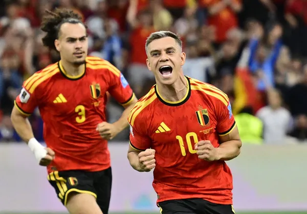Trossard runs forward, celebrating his goal, while a teammate follows close behind