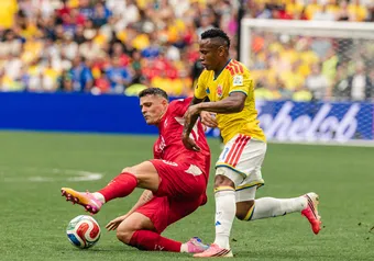 A Swiss player comes in for the tackle while a Colombian player attempts to move the ball up the pitch.
