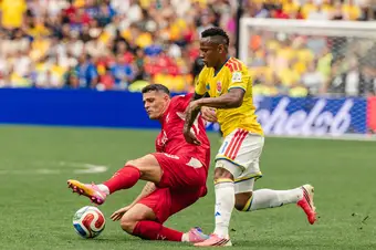 A Swiss player comes in for the tackle while a Colombian player attempts to move the ball up the pitch.