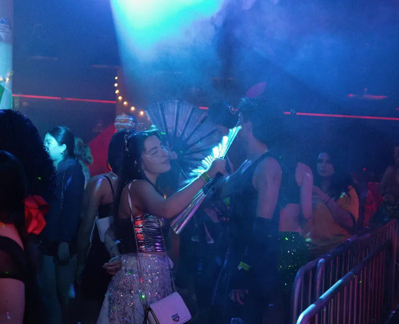 A woman dances in a club with fans in her hands.