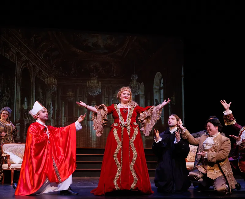 A photo of a woman in a red dress with her arms pointing to the sky.