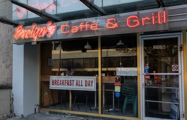 The front door of Evelyn's Cafe and Bistro with a neon sign above it.