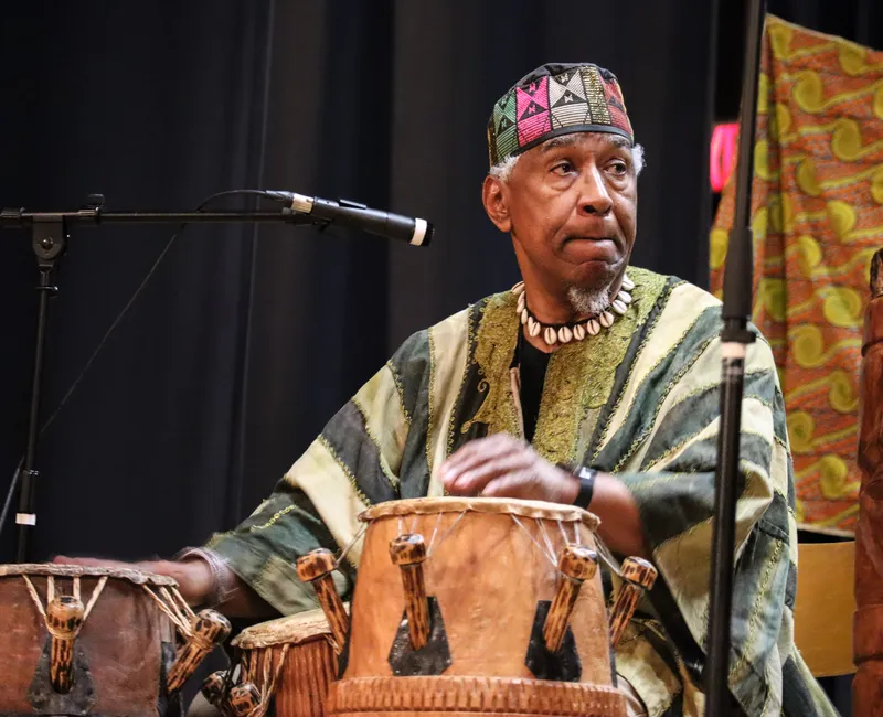 A man plays drums in traditional African clothing