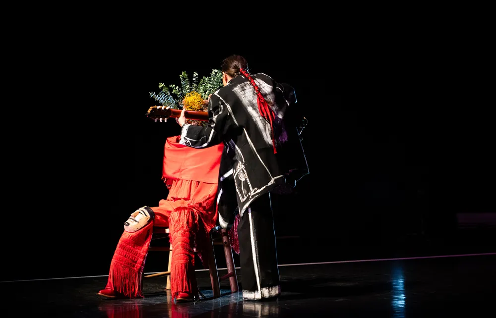 A woman plays to a figure made of flowing red clothing