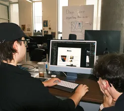 Desktop monitor displaying illustration software showing The Ubyssey's icon being redesigned.
