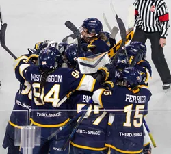The UBC women's hockey team celebrates in a dog pile after winning.